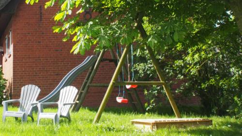 a playground with two white chairs and a swing at Ferienwohnung Wattwurm Ockholm in Ockholm