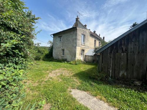 an old building in a field next to a fence at Appartement indépendant dans maison en pierre in Coeuvres-et-Valsery