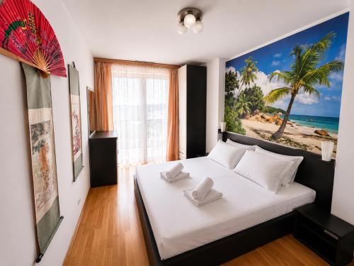 a bedroom with a white bed with a picture of a beach at Coralia Luna Park Apartments in Mamaia