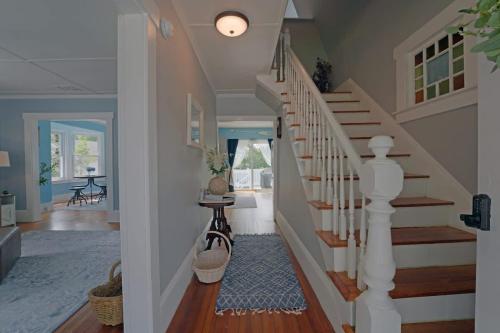 a hallway with a white staircase with a rug at Beautiful Modern Beach House! in Old Orchard Beach