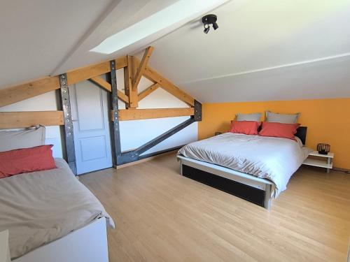 two beds in a room with orange walls and wooden floors at Feutres et Formes in Bourg-de-Péage