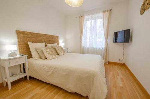 a white bedroom with a large white bed and a television at La bulle champêtre in Balnot-sur-Laignes