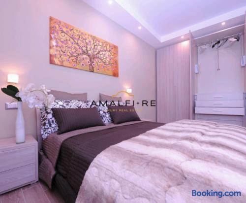 a bedroom with a large bed and a painting on the wall at Casa Serena in Amalfi