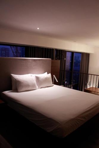 a bedroom with a large white bed with a window at Casahindout in Hanoi