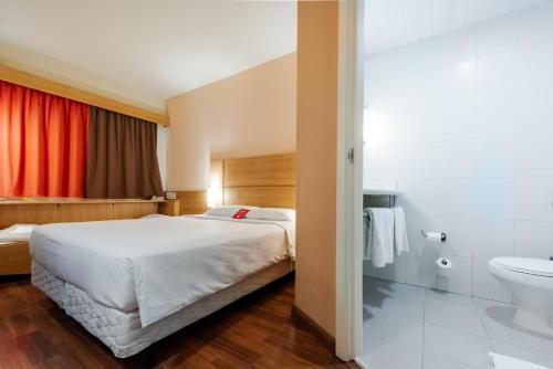a bedroom with a bed and a bathroom with a toilet at ibis Novo Hamburgo in Novo Hamburgo