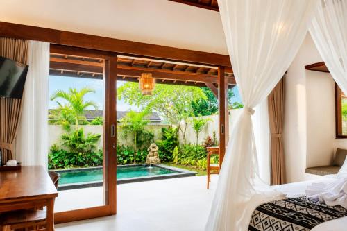 a bedroom with a bed and a view of a pool at Akar Villa in Ubud