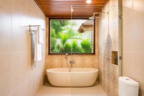 a bathroom with a bath tub and a window at Akar Villa in Ubud