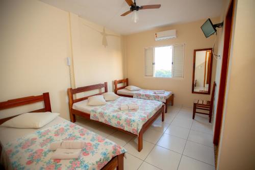 a room with two beds and a mirror at Hotel Caminho do Rosário in Aparecida