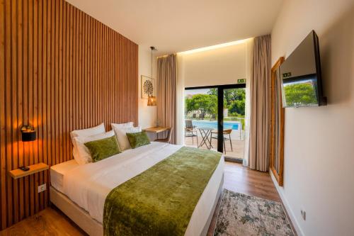 a bedroom with a large bed and a balcony at Moinho do Canto Residence Hotel in Rio Maior