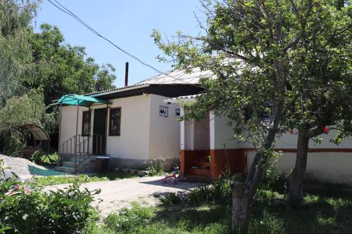 a small white house with a tree in front of it at Bulak - Kyrgyz Family Hostel in Karakol