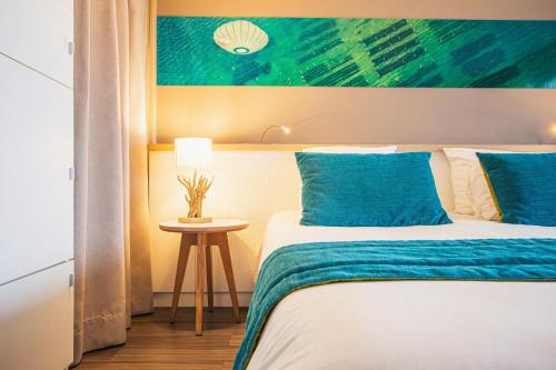 a bedroom with a bed with blue pillows and a painting at Hôtel Le B d'Arcachon by Inwood Hotels in Arcachon