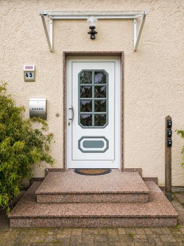 a white front door of a house with stairs at Pension Greifswald in Dargelin