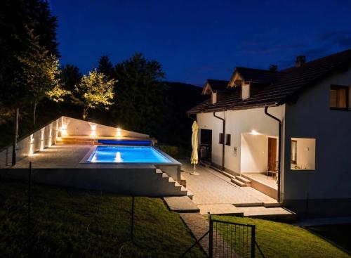 a swimming pool with lights next to a house at Holiday House Marija in Otočac