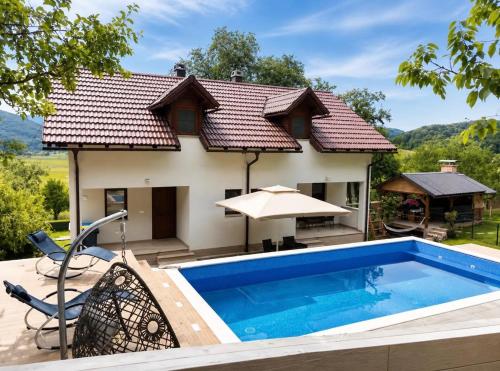 a house with a swimming pool in front of a house at Holiday House Marija in Otočac