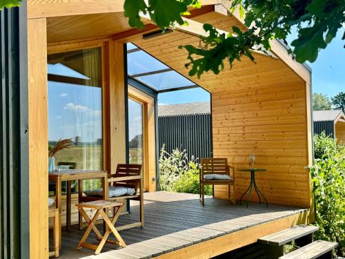 a wooden deck with a table and chairs on a house at 204 Hochwertiges Tiny House mit Wiesenblick in Bleckede