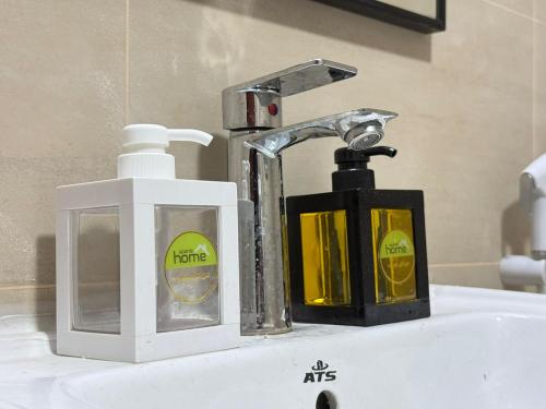 a bathroom sink with a faucet and two soap containers at Unmatched Location - A Large 2BR Sea-facing Flat in Sharjah