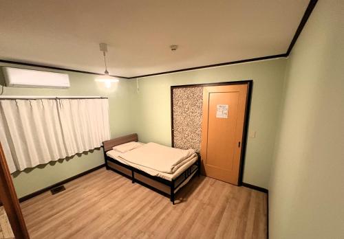a small room with a bed and a window at Frasis in Furano