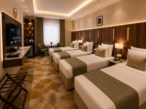 a hotel room with four beds and a television at هندباء Hindibaa in Mecca