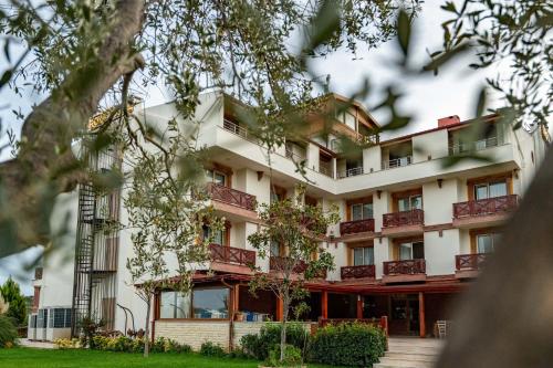 a building with balconies and trees at Helen Troya Hotel Geyikli in Çanakkale