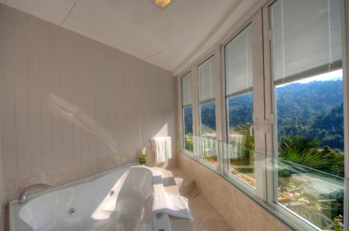 a bathroom with a tub and a large window at The Chateau Spa & Wellness Resort in Bukit Tinggi