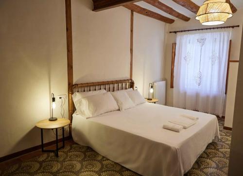 a bedroom with a white bed with two tables and a window at Masía El Losar - Casa Rural Exclusiva Castellón in Villafranca del Cid