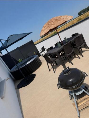 a grill and a table with an umbrella on a building at Évasion détente in Heiltz-le-Hutier