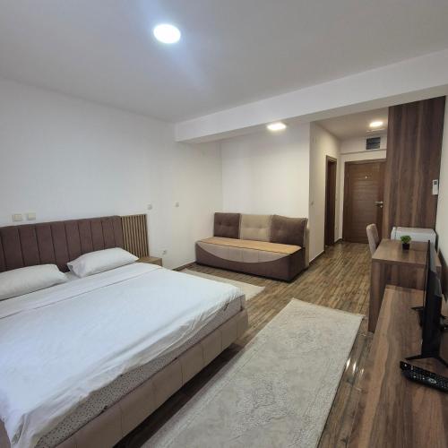 a bedroom with a large bed and a couch at Apartmani Han in Bijelo Polje