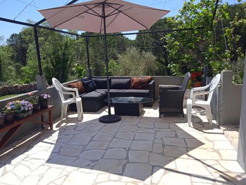 a patio with a couch and an umbrella at Вилла Загора in Neodi