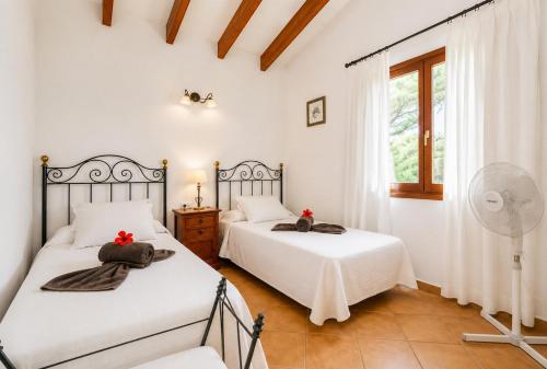 two beds in a bedroom with white walls and a window at Villa Estrella in Cala en Blanes