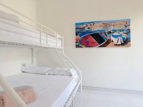 a white bed in a white room with a picture on the wall at Villetta Chiara in Baia Verde