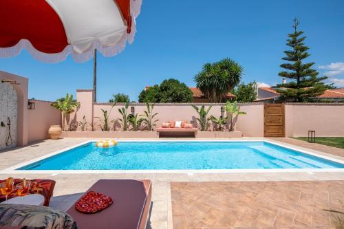 a swimming pool with chairs and an umbrella at Casa Tortuga - Exclusive Villa Corfu in Acharavi