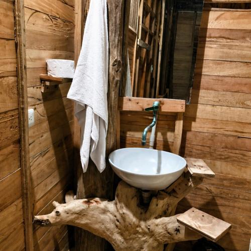 a bathroom with a sink on top of a log wall at Bungalow Palmar del Viento by AMAUNA in Moñitos