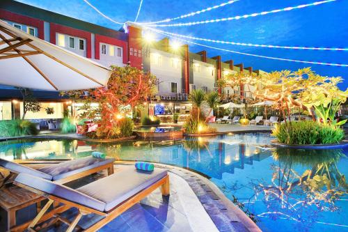 a hotel pool with chairs and an umbrella at Swiss-Belhotel Kendari in Kendari