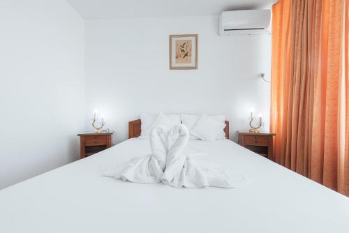 białe łóżko w sypialni z dwoma stolikami w obiekcie Hotel Scoica w mieście Jupiter