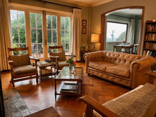 a living room with a brown leather couch and chairs at Hotel El Ciervo in Villarrica