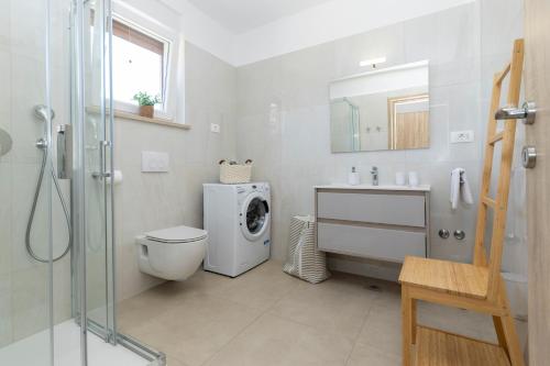 a bathroom with a toilet a sink and a washing machine at Villa Egli s bazenom in Kršan