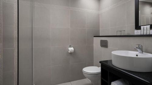 a white bathroom with a sink and a toilet at Protea Hotel by Marriott Cape Town Tyger Valley in Bellville