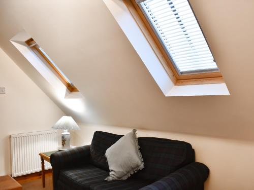 a living room with a black couch and a skylight at Sycamore Cottage - Uk45923 in Ballater
