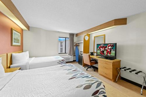 a hotel room with a bed and a desk with a television at Red Roof Inn Branson in Branson
