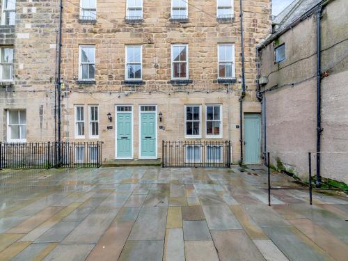 an empty courtyard of an old brick building with blue doors at Town Square House - Uk45610 in Alnwick