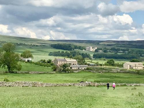 two people walking in a field with a stone wall at The Owlery At Aysgarth in Aysgarth