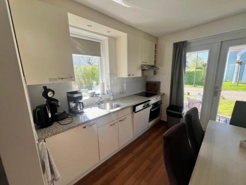a kitchen with white cabinets and a sink and a window at Aquadelta - Casa Claudia in Bruinisse