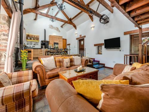 a living room with couches and a tv at Wheelwright Barn in Llangain