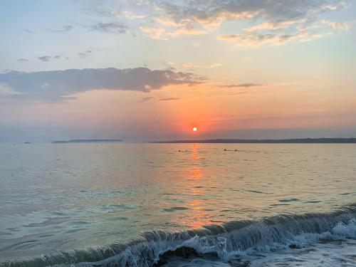 a sunset over the ocean with a wave at The Lodge in Uny Lelant