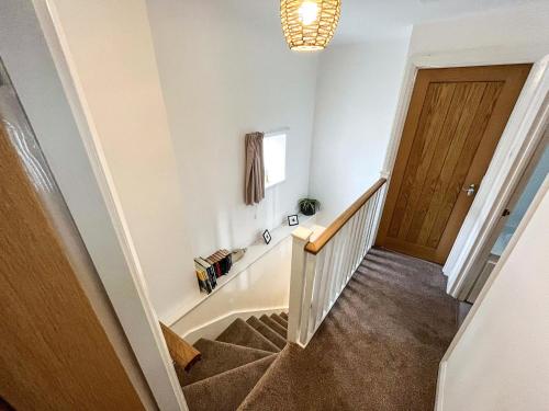 a hallway with a staircase with a wooden door at Willesdene Cottage in Abernethy