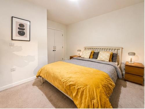 a bedroom with a large bed with a yellow blanket at Stunning 1 Bed Luxury Apartment in Erith
