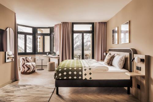 a bedroom with a bed in a room with windows at Hotel Altein Arosa, a Faern Collection Resort in Arosa