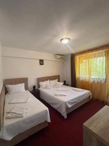 two beds in a hotel room with a window at Hotel Ibiza in Eforie Nord