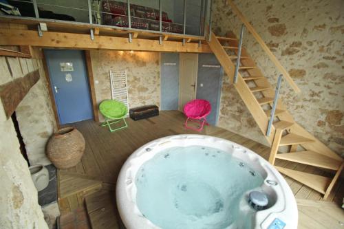 a bath tub in a room with two chairs and a staircase at Les cheyroux in Saint-Léger-Magnazeix