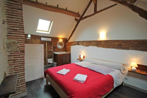 a bedroom with a red bed in a brick wall at Les cheyroux in Saint-Léger-Magnazeix